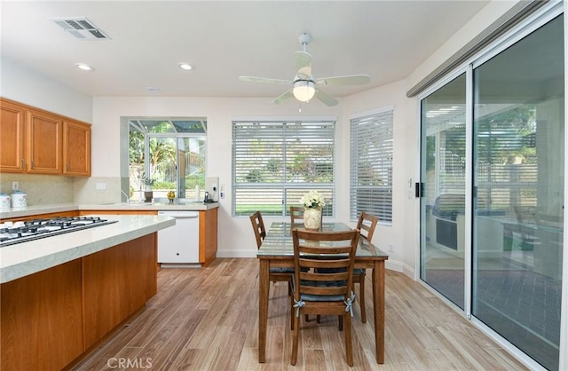 kitchen featuring ceiling fan, stainless steel gas cooktop, tasteful backsplash, white dishwasher, and light wood-type flooring