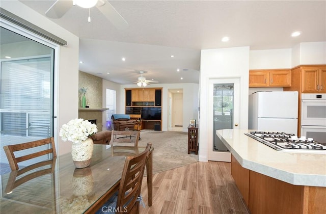 kitchen featuring ceiling fan, white appliances, and light hardwood / wood-style flooring