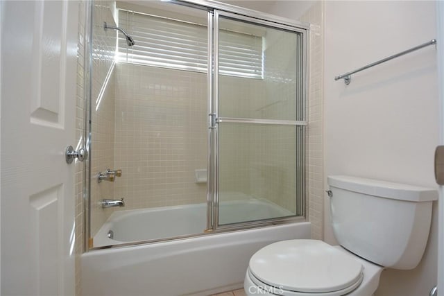 bathroom with bath / shower combo with glass door and toilet