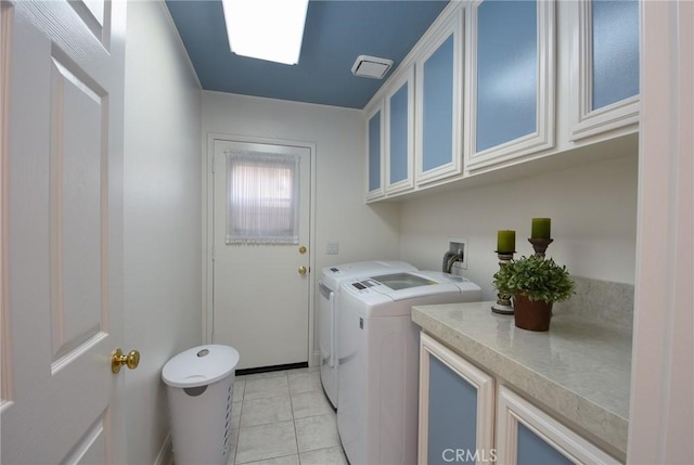 clothes washing area featuring cabinets, light tile patterned floors, and washing machine and dryer