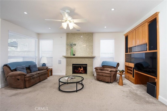 carpeted living room with a large fireplace and ceiling fan