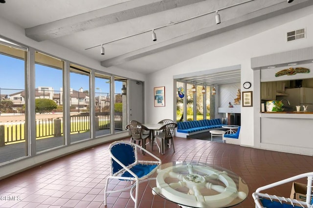 interior space featuring lofted ceiling with beams, rail lighting, and a wealth of natural light