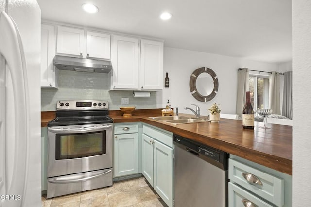 kitchen with sink, stainless steel appliances, tasteful backsplash, butcher block countertops, and white cabinets