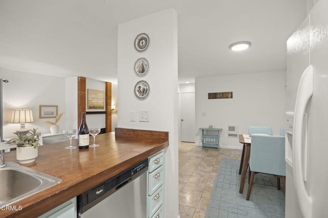 kitchen with butcher block countertops, sink, stainless steel dishwasher, and white refrigerator with ice dispenser