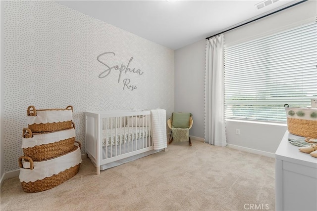 carpeted bedroom featuring a nursery area