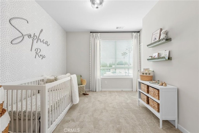 bedroom featuring light carpet and a nursery area