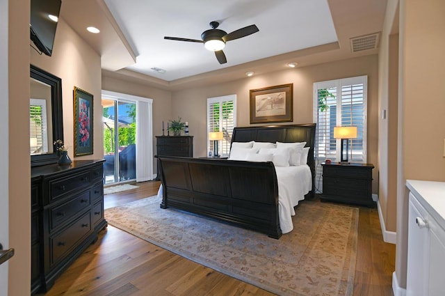 bedroom featuring hardwood / wood-style flooring, ceiling fan, access to exterior, and multiple windows