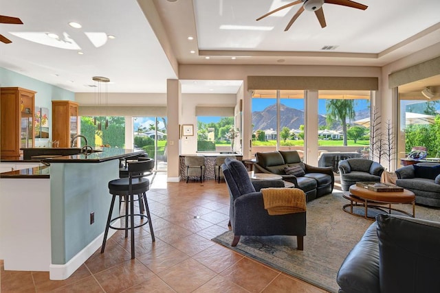 tiled living room with a mountain view, a healthy amount of sunlight, and ceiling fan