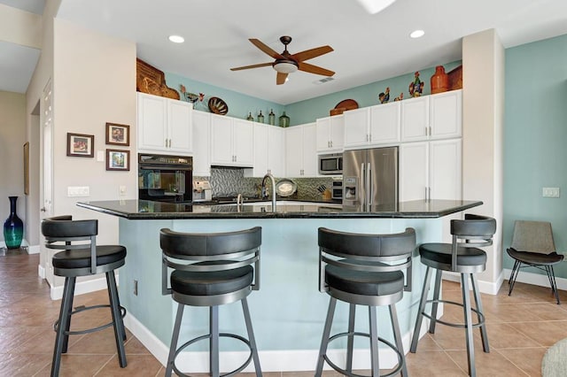 kitchen featuring a kitchen island with sink, a breakfast bar, white cabinets, and appliances with stainless steel finishes