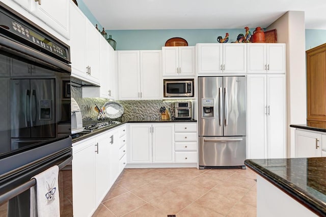 kitchen featuring decorative backsplash, appliances with stainless steel finishes, dark stone counters, light tile patterned floors, and white cabinets