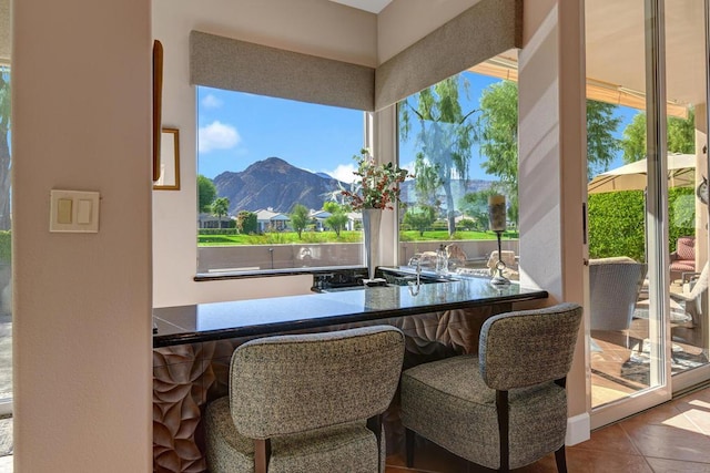 dining room with tile patterned floors, bar area, a mountain view, and plenty of natural light