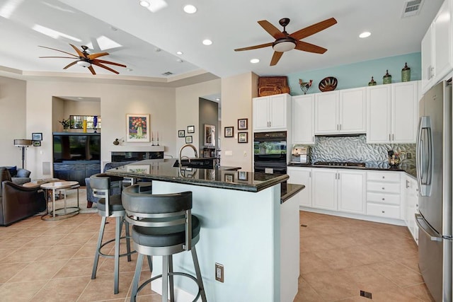 kitchen featuring white cabinets, backsplash, stainless steel appliances, and a breakfast bar area