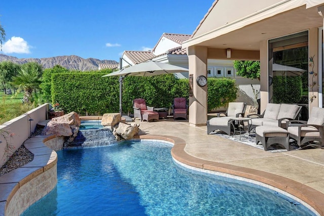 view of swimming pool featuring pool water feature, a mountain view, an in ground hot tub, and a patio