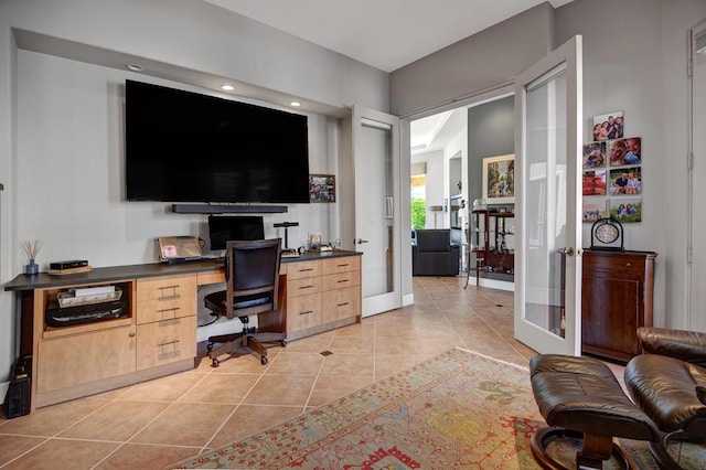 office with french doors, built in desk, and light tile patterned floors