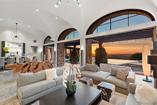 living room featuring a water view, high vaulted ceiling, and a chandelier