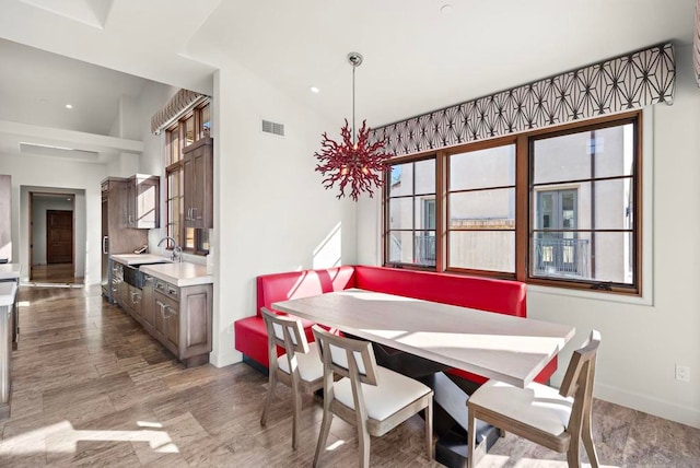 dining area featuring hardwood / wood-style flooring, vaulted ceiling, a healthy amount of sunlight, and sink