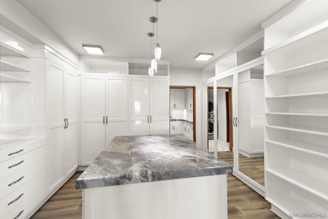 spacious closet with stacked washer / dryer and dark hardwood / wood-style flooring