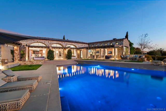 pool at dusk featuring a patio