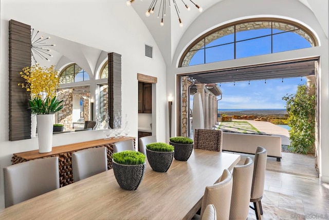 dining room featuring high vaulted ceiling and a chandelier