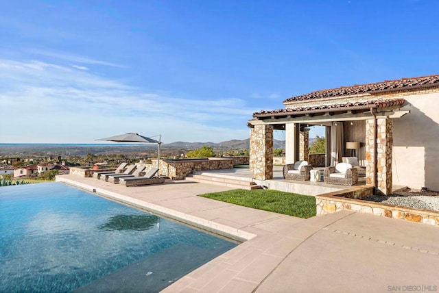 view of pool with a mountain view, a patio area, and an outdoor fireplace