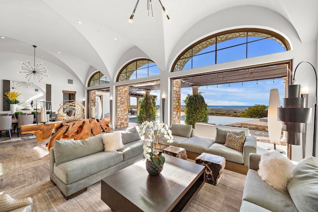 living room with a water view, high vaulted ceiling, and a chandelier