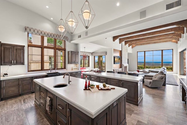 kitchen featuring beamed ceiling, a center island with sink, a wealth of natural light, and sink