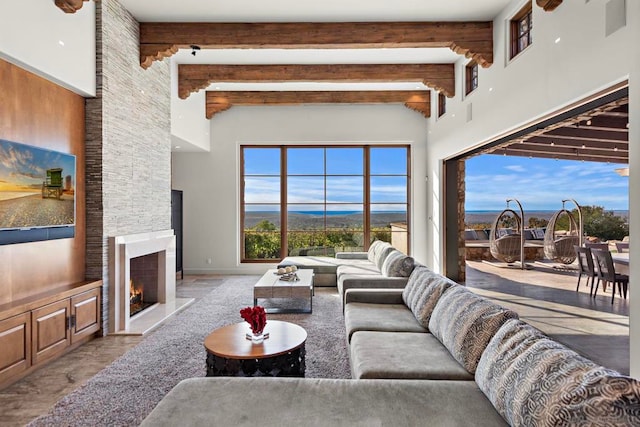 living room with a high ceiling, a stone fireplace, and beam ceiling