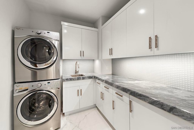 clothes washing area with sink, cabinets, and stacked washer and clothes dryer