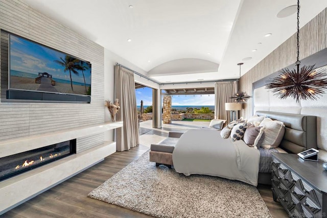 bedroom with lofted ceiling, a fireplace, and dark hardwood / wood-style floors