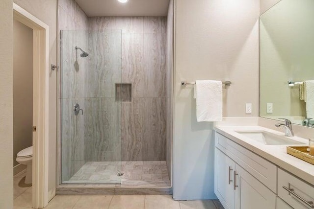 bathroom with tile patterned floors, a shower with door, vanity, and toilet