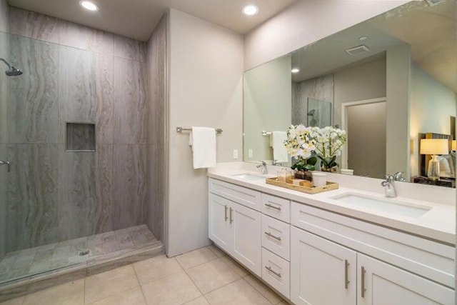 bathroom featuring tile patterned flooring, vanity, and a tile shower