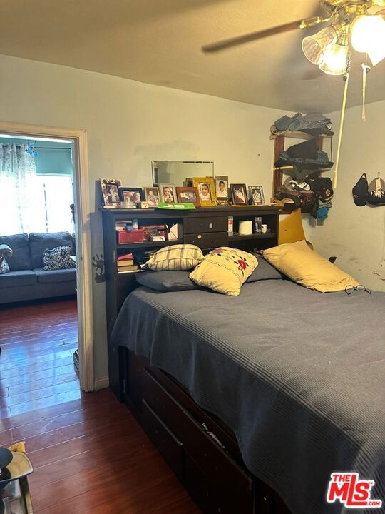 bedroom with dark hardwood / wood-style flooring and ceiling fan