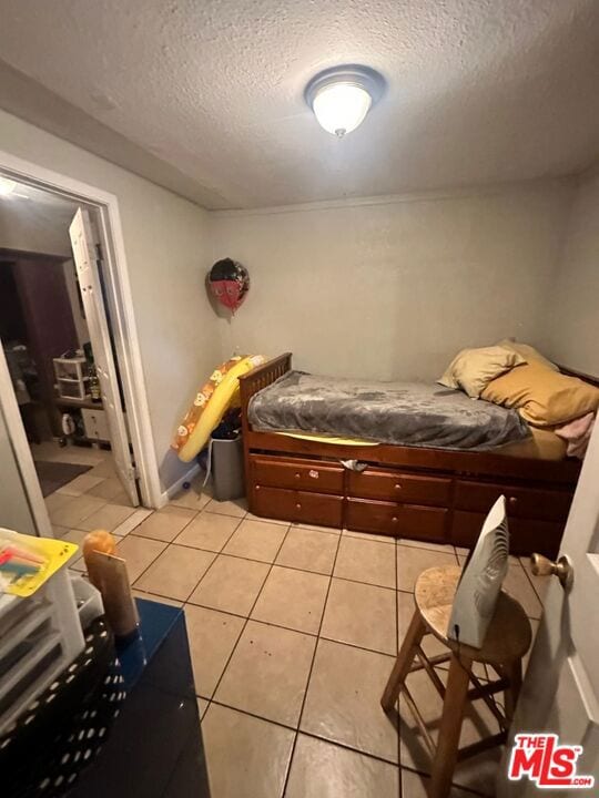 bedroom featuring light tile patterned floors and a textured ceiling