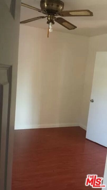 empty room with ceiling fan and dark wood-type flooring