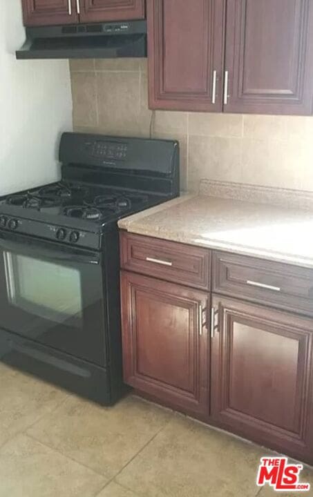 kitchen with gas stove, light tile patterned floors, and backsplash