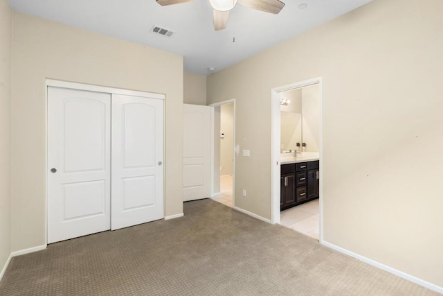 unfurnished bedroom with ceiling fan, light colored carpet, connected bathroom, and a closet