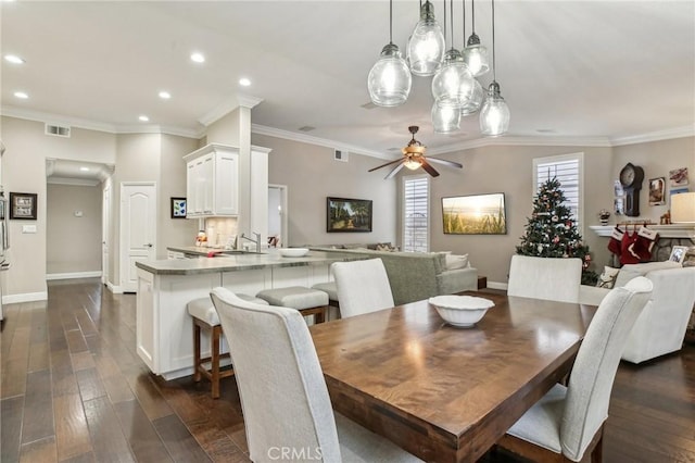 dining area featuring ceiling fan, dark hardwood / wood-style flooring, ornamental molding, and sink