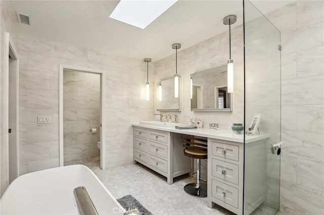 bathroom featuring a skylight, vanity, and tile walls