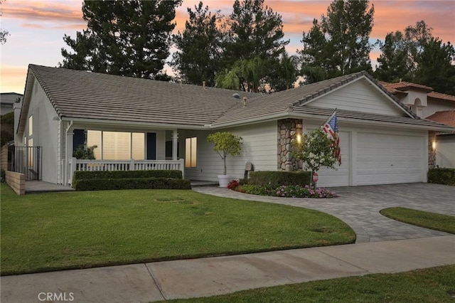 ranch-style house with a lawn, a porch, and a garage