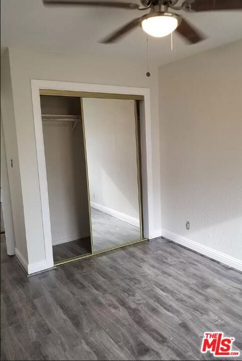 unfurnished bedroom featuring a closet, dark hardwood / wood-style floors, and ceiling fan