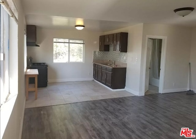 kitchen with black range with electric cooktop, tasteful backsplash, range hood, dark brown cabinets, and light wood-type flooring