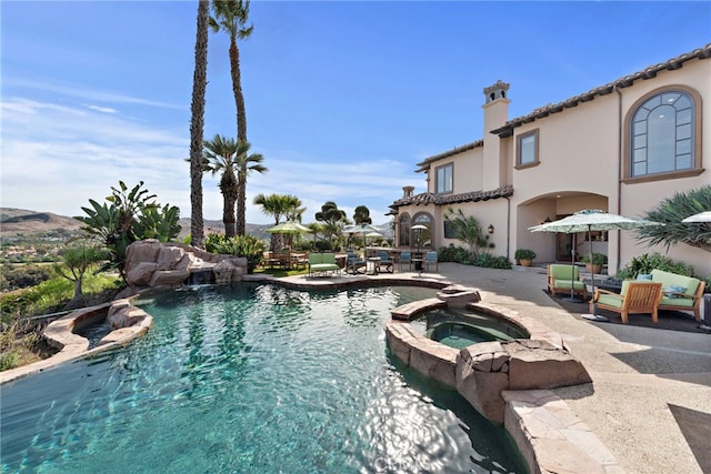 view of swimming pool featuring pool water feature, a patio area, and an in ground hot tub