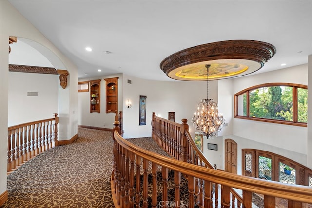 hall featuring carpet flooring and a notable chandelier