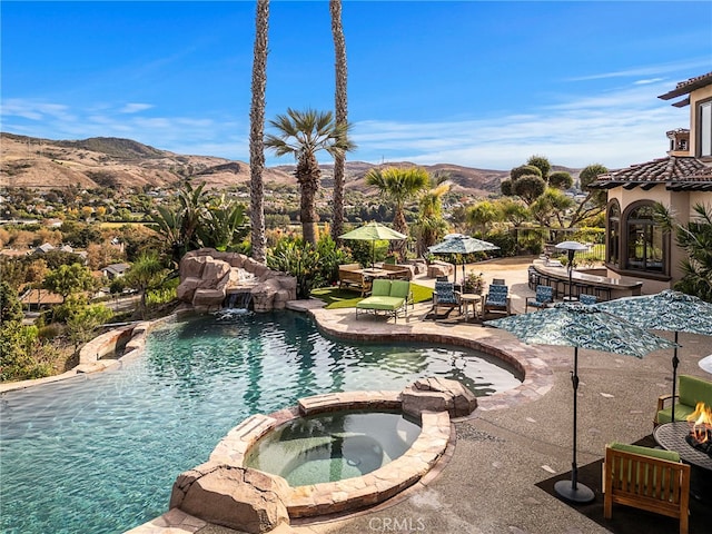 view of swimming pool featuring a mountain view, a patio, and an in ground hot tub