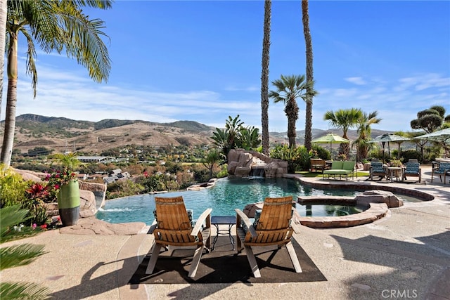 view of pool with a mountain view, pool water feature, an in ground hot tub, and a patio area