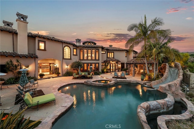 pool at dusk with an in ground hot tub, a gazebo, and a patio area