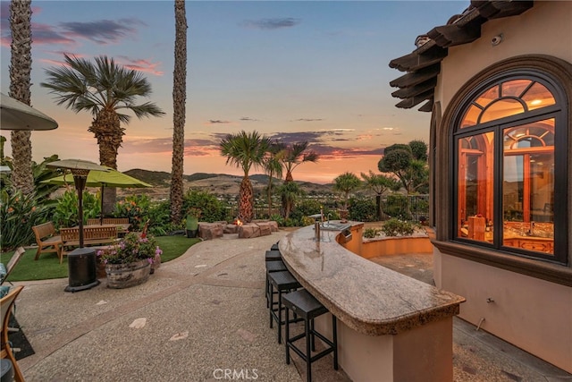 patio terrace at dusk featuring a mountain view and an outdoor bar