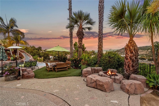 yard at dusk featuring an outdoor fire pit and a patio area