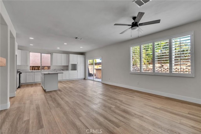 kitchen featuring white cabinets, light hardwood / wood-style floors, a kitchen island, and ceiling fan