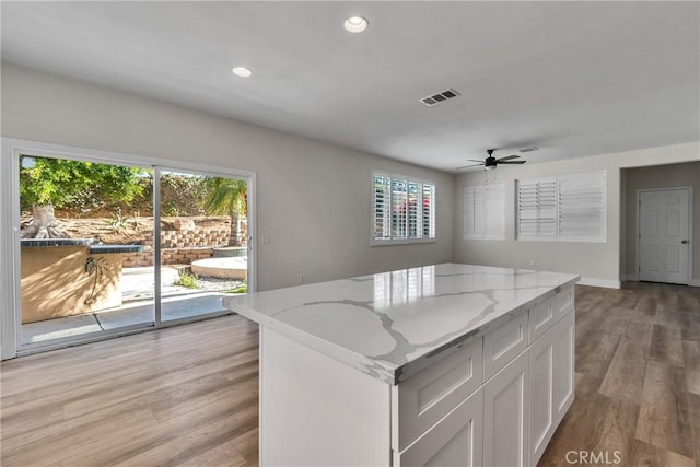 kitchen with white cabinetry, plenty of natural light, light stone countertops, and light wood-type flooring